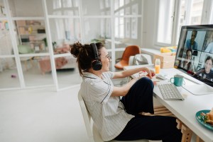 Girl wearing headphones smiling at computer screen attending video call.