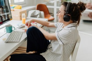Woman smiling wearing headphones attending a webinar.