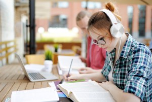Girl with glasses wearing headphones while studying.