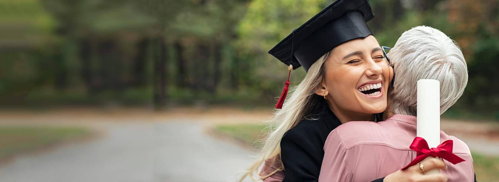 Smiling female college graduate achieves her goal while hugging her mother.