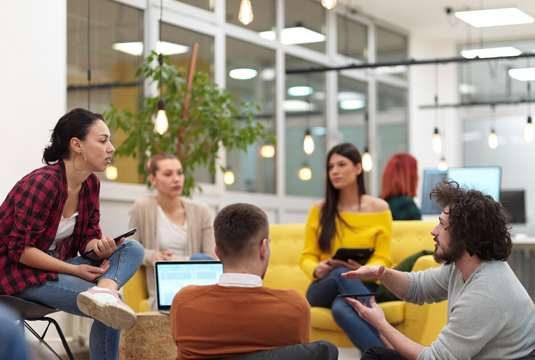 Five college students sitting in a circle around a table, having a discussion.