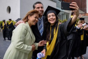 Female College graduate taking selfie with mother and father