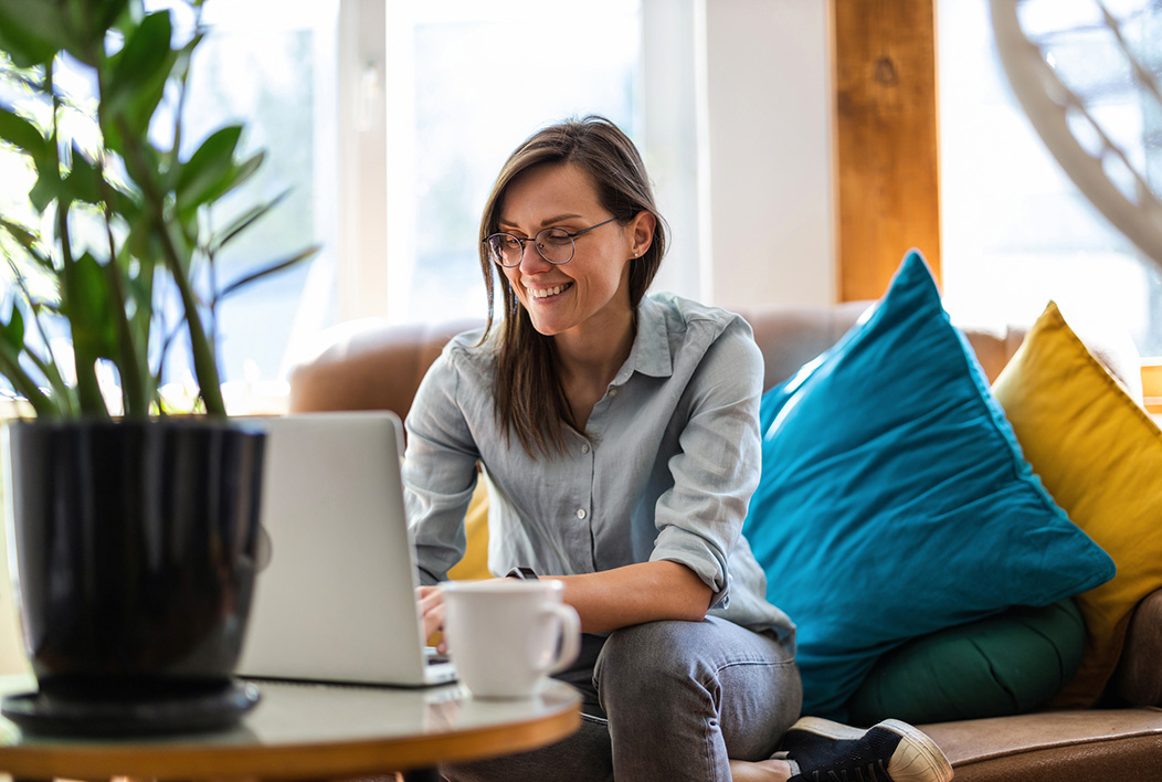 Woman sitting on a couch looking at laptop.