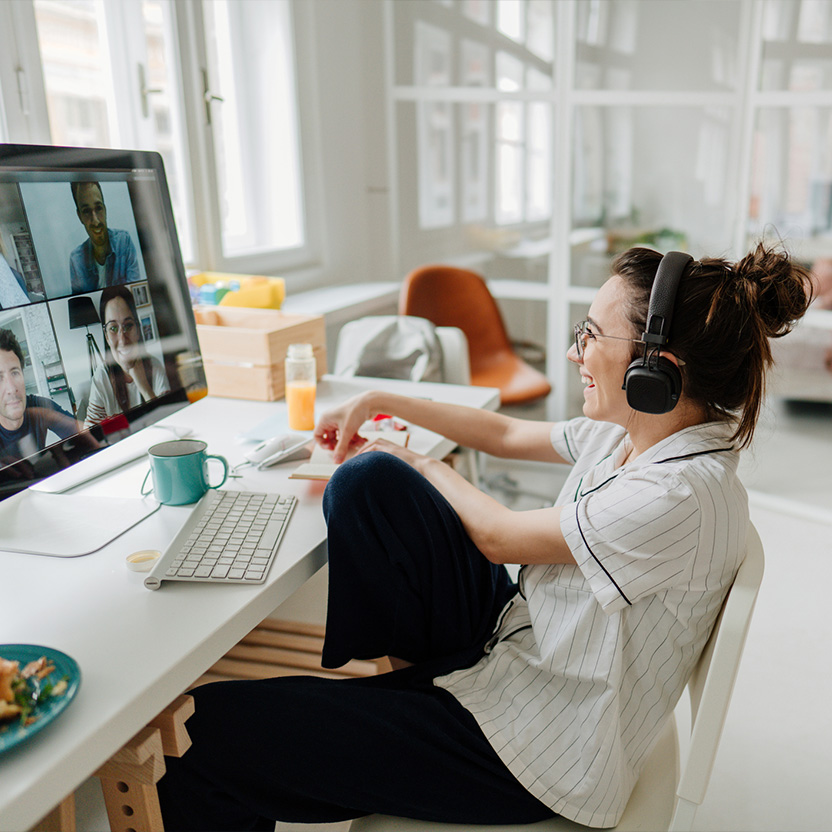 Female college student wearing headphones participating in a video call with three other people.