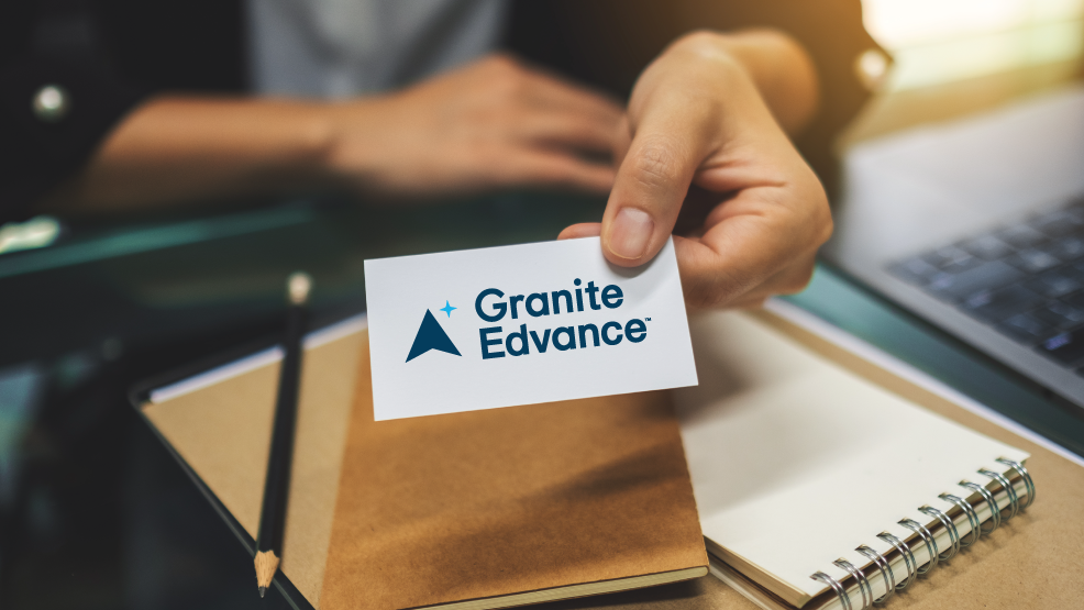 Hand leaning on a desk displaying a business card with Granite Edvance logo to announce new brand.