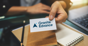 Hand leaning on a desk displaying a business card with Granite Edvance logo to announce new brand.