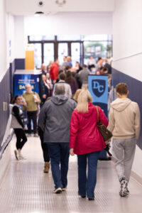 Students and families walk down a hallway, their backs to us, at Destination College.