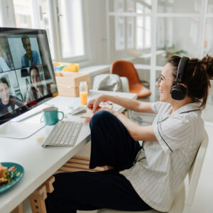 Woman smiling wearing headphones attending a webinar